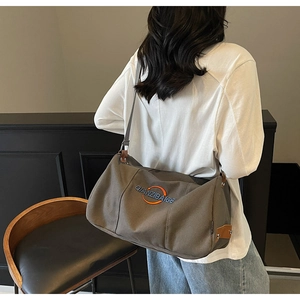 Sac bandoulière en toile café foncé avec détails en cuir et sangle réglable sur modèle