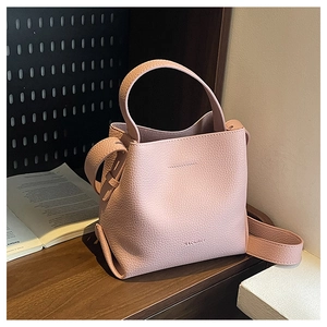 Detail of pink lychee leather texture and handle on a mini trapezoid bucket bag