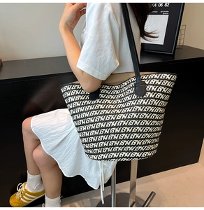 Dettaglio della borsa tote intrecciata con motivo a onde bianco e nero e manici in ecopelle