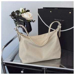 Close-up of beige tote bag with smooth nylon texture and adjustable shoulder strap