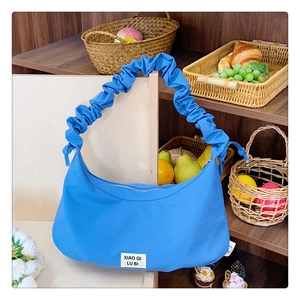 Detailaufnahme der blauen Falten-Tasche mit Markenetikett auf einem rustikalen Regal