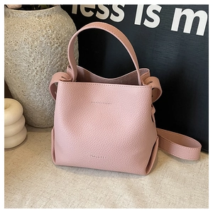 Close-up of a pink lychee grain bucket bag with brand logo and minimalist decor