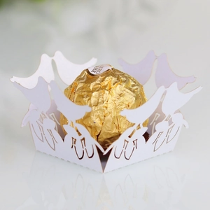 Macro view of white laser-cut hollow bird candy holder with gold chocolate for wedding party