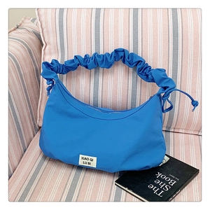 Detail der blauen sichelförmigen Schultertasche mit Falten-Griff auf weichem Sofa