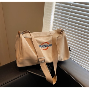 Gros plan du sac cabas en toile beige avec logo brodé sur un banc en cuir noir