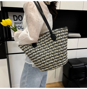 Dettaglio della borsa tote intrecciata con motivo geometrico e tracolla in pelle nera su modella