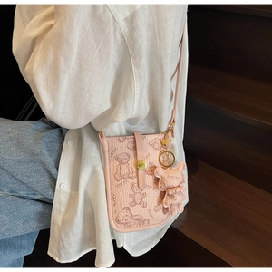 Close-up of pink crossbody phone bag with teddy bear print and hanging bear charm