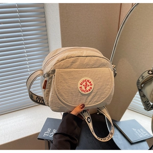 Detail of a beige nylon crossbody bag with branded embroidery and wide logo strap
