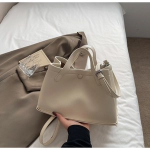 Detail of cream lychee leather bucket bag with silver hardware on casual home background