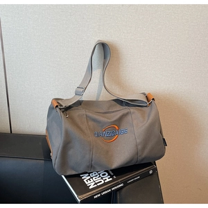 Détail du sac cabas en toile grise avec logo brodé et passepoil en cuir marron