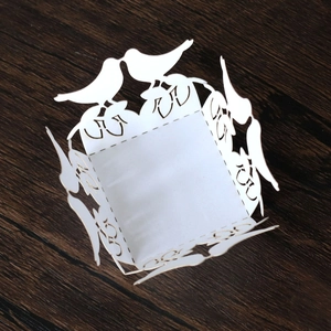 Macro detail of laser-cut white paper bird candy box with intricate floral pattern