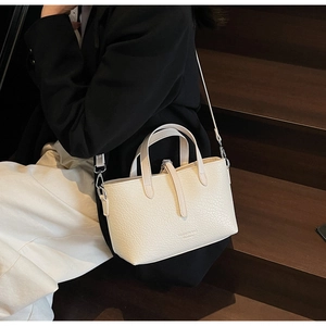 Detail of minimalist cream crossbody bag with leather texture and silver hardware