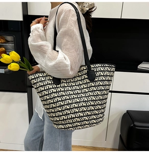 Dettaglio della borsa tote intrecciata bianca e nera con tracolla in pelle nera