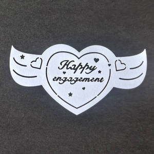 Détail du marque-place en forme de cœur ailé avec texte Happy Engagement pour fête