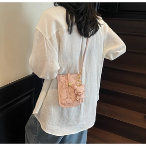 Detail of pink crossbody phone bag with bear patterns and cute mascot charm decoration