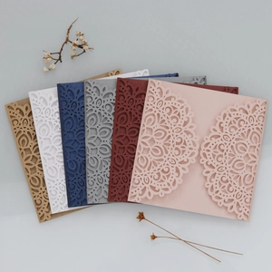 Detail of laser-cut lace patterns on pearlescent paper invitation cards in various colors
