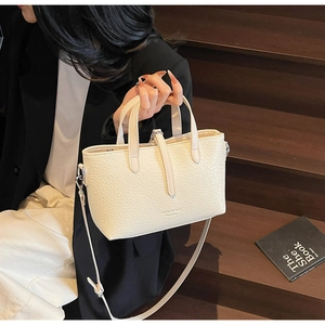 Detailed close-up of cream white crocodile texture handbag held by a fashion model