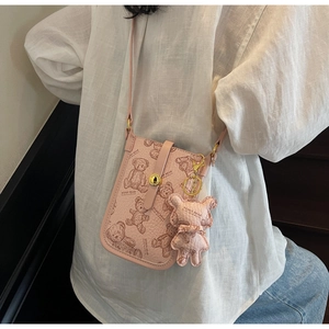 Close-up of pink crossbody phone bag featuring a cute teddy bear print and matching charm