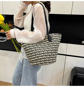 Vista dettagliata della borsa tote tessuta con motivi bianchi e neri e manici in pelle