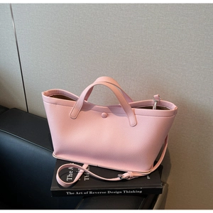 Detail of light pink pebble grain bucket bag with dual handles and circular buckle