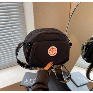 Detailed view of black nylon crossbody bag with geometric jacquard strap and round logo