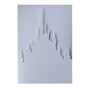 Macro detail of laser-cut 3D white castle silhouette invitation card with layered texture