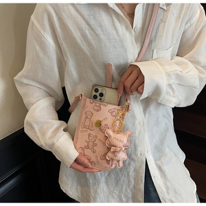 Detail of pink crossbody phone bag with teddy bear pattern and golden buckle strap