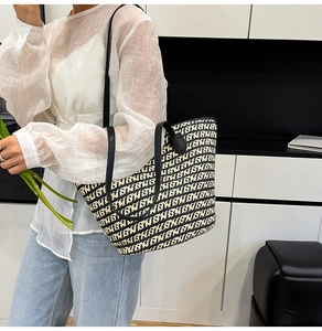 Dettaglio della borsa tote intrecciata con motivi geometrici bianchi e neri e manici in pelle