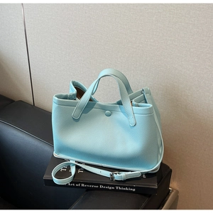 Macro shot of mint green pebbled leather tote bag with round buckle and adjustable strap