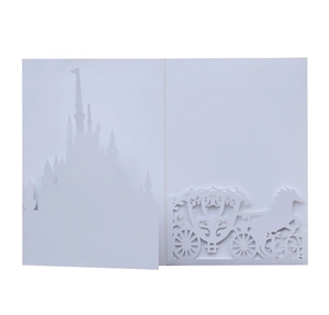 Detailed laser-cut white wedding invitation card featuring a castle and carriage silhouette