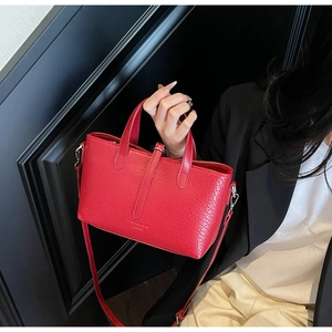Detail of red crocodile pattern handbag showing dual handles and detachable shoulder strap