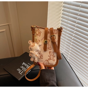 Detail of cream crossbody phone bag with teddy bear print and brown leather straps