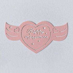 Détail d'une carte cœur découpée au laser rose avec ailes Happy Engagement pour fête
