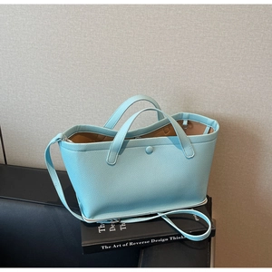 Close-up of light blue lychee pattern tote bag on a black book with grey background
