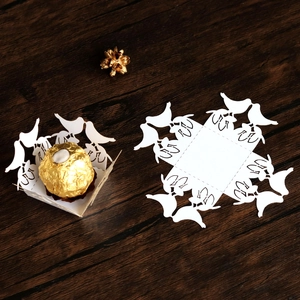 Macro detail of laser-cut wedding candy box with bird pattern on wood background