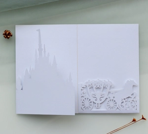Detailed laser-cut white wedding invitation with elegant castle and carriage silhouette