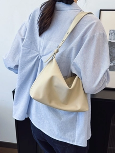 Chic cream leather tote bag with adjustable shoulder strap worn by a model in a casual setting