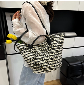 Dettaglio della borsa tote intrecciata con motivi geometrici neri e bianchi e manici neri