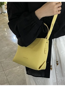 Vibrant yellow lychee pattern leather bucket bag shown as a crossbody on a model