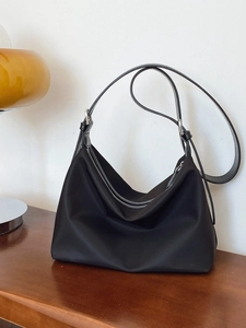 Minimalist black nylon tote bag on a wooden desk next to a vintage yellow lamp