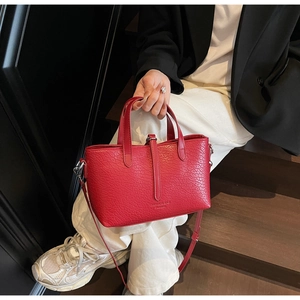Detailed macro view of the red animal pattern texture and adjustable strap on the handbag