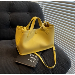 Detail of yellow pebbled leather tote bag featuring silver hardware and adjustable strap