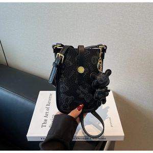 Detail view of black pebble leather crossbody bag featuring grey teddy bear prints