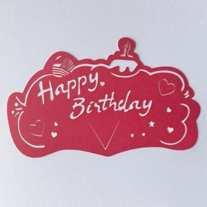 Macro shot of red Happy Birthday paper card with hollowed out cake and star motifs