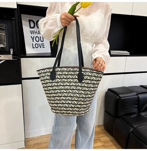 Dettaglio della borsa tote intrecciata con motivi geometrici neri e beige e manici