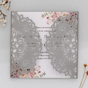 Détail macro du faire-part de mariage argenté découpé au laser avec carte à fleurs