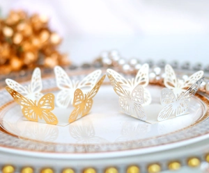 Detail of 3D laser-cut hollow butterfly decorations with gold mirror finish on a porcelain plate