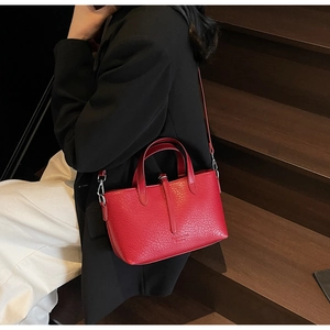 Detail of red faux leather handbag with stone texture and adjustable shoulder strap