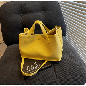Detailed texture of bright yellow lychee leather handbag on a dark corduroy chair