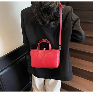 Model wearing a red crocodile pattern tote bag to show size and scale on stairs